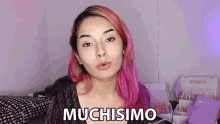 a woman with pink hair says muchisimo in front of a box