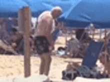 a man is standing on a beach under an umbrella with a microphone .