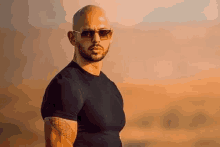 a bald man with a beard wearing sunglasses and a black shirt .