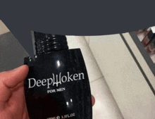 a person is holding a black bottle of deep taken for men