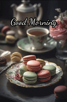 a plate of macarons sits on a saucer next to a cup of tea and the words good morning