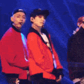 a group of young men are standing on a stage with microphones in their mouths .