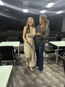 two women are posing for a photo in front of a sign that says god