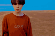 a young man wearing a brown shirt that says regret on it