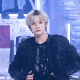 a man with blonde hair is wearing a black jacket and a black shirt