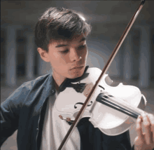 a young boy is playing a white violin