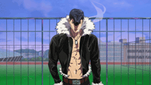 a man in a black jacket with a white fur collar stands in front of a fence