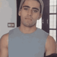 a man wearing a beanie and a tank top is looking at the camera