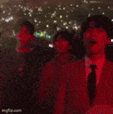 a man in a suit and tie is standing in front of a crowd at a concert .