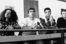 a group of men sitting at a table with microphones in front of them