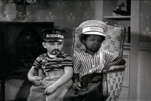 a black and white photo of two boys wearing hats that say 2nd messenger .