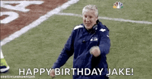 a man is standing on a football field with the words `` happy birthday jake '' written on it .