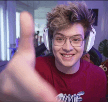 a young man wearing glasses and headphones is smiling and giving a thumbs up sign