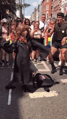 a group of people are gathered on a street including a man wearing a black shirt with a rainbow flag on it