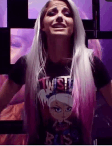 a woman with long white hair and pink highlights is wearing a black t-shirt with a cartoon character on it .