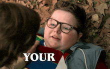 a boy with glasses is laying on the ground and the word your is on the bottom right