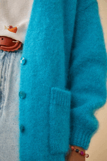 a person wearing a bright blue cardigan with buttons