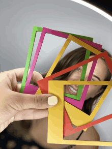 a woman 's face is behind a stack of colorful frames