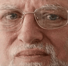 a close up of a man with glasses and a beard making a funny face .