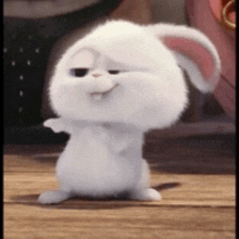 a white rabbit from the secret life of pets is standing on a wooden floor and smiling .