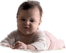 a baby is laying on its stomach on a white background making a funny face .