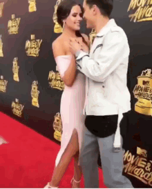 a man and woman are standing on a red carpet in front of a wall that says movie & tv awards