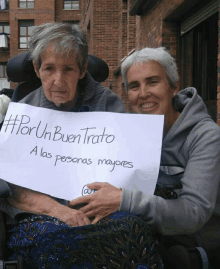 a woman in a wheelchair holds up a sign that says #por un buen trato