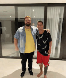 two men standing next to each other with one wearing a shirt that says bats