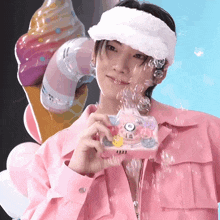 a man wearing a pink jacket and a white headband is holding a bubble machine