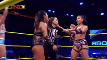 a female wrestler is being held by a referee in a wrestling ring