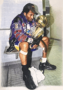 a man in a purple jacket with the letter b on it sits on a bench holding a trophy