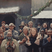 a group of people are clapping in front of a building with a sign that says ' a ' on it