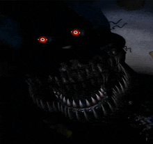 a close up of a monster 's face with red eyes and sharp teeth in the dark .