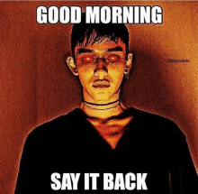 a man with red eyes is standing in front of a wall with the words `` good morning say it back '' written on it .