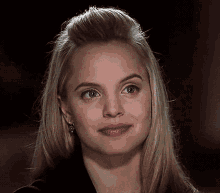 a close up of a woman 's face with a slight smile on her face