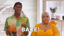 a man in a green shirt and a woman in a yellow dress are standing next to each other and the woman is saying bake