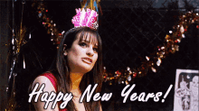 a woman wearing a new year 's eve hat is standing in front of a sign that says `` happy new years '' .