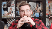 a man in a plaid shirt is eating a sandwich in front of a shelf that says dubstep