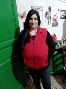 a woman wearing a red vest stands in front of a wall with a calendar on it