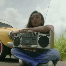 a woman is kneeling down holding a boombox in front of a car .