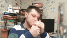 a man smoking a cigarette in front of a stack of books one of which is titled " l' ottomano "