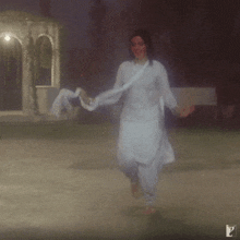 a woman in a white dress is dancing in front of a gazebo with the letter p in the corner