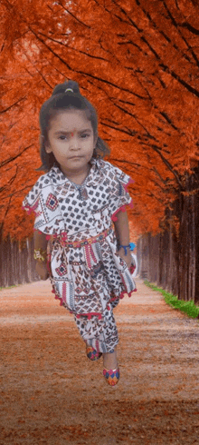 a little girl in a white and black dress is running down a path