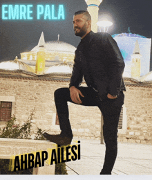 a man kneeling in front of a building with the name emre pala