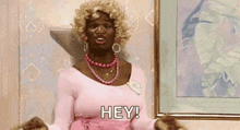 a woman in a pink dress is saying hey .