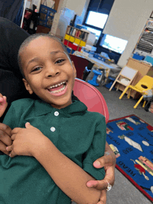 a young boy in a green shirt is smiling in front of a rug that says read