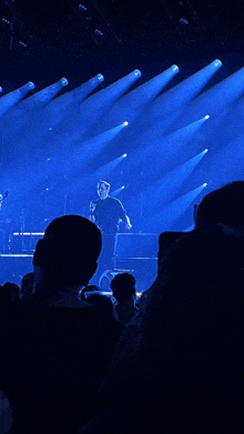 a man in a black shirt is standing on a stage with a microphone in his hand