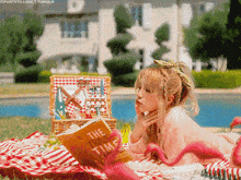 a girl laying on a picnic blanket reading the time