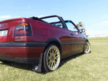 a red car with the license plate 95 ec is parked in the grass