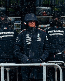 a man wearing a petronas jacket stands in the snow